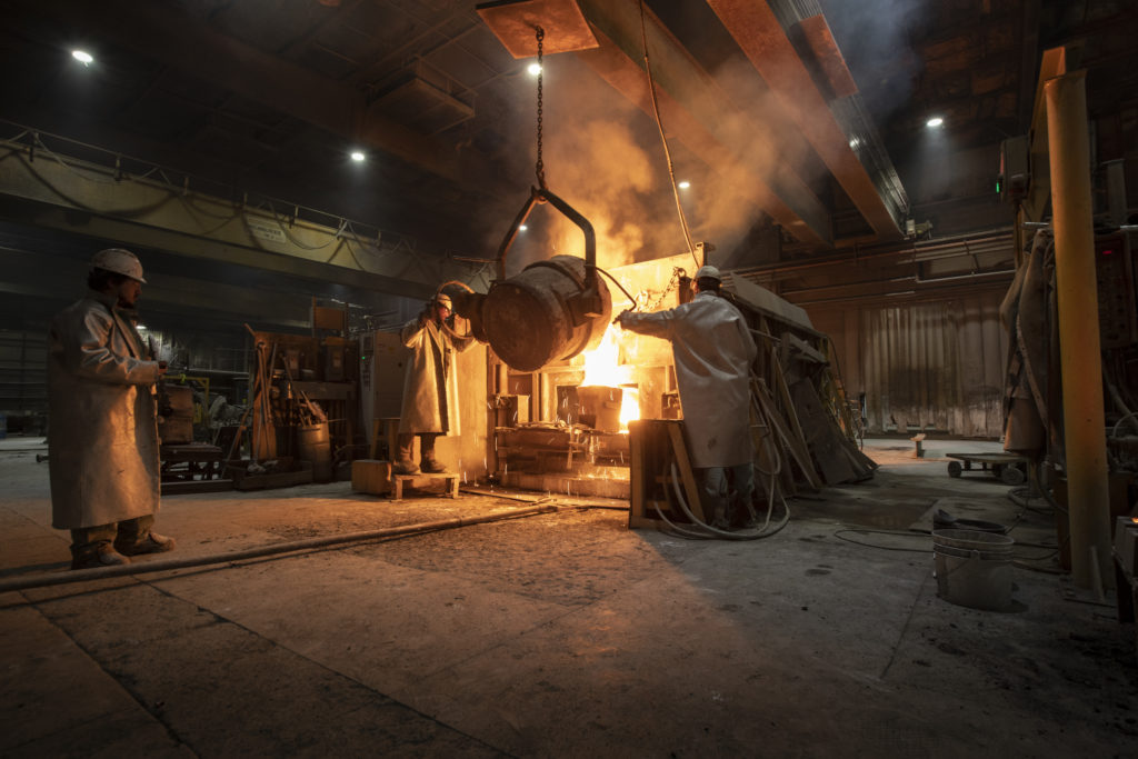 Three employees working with metal in the foundry.