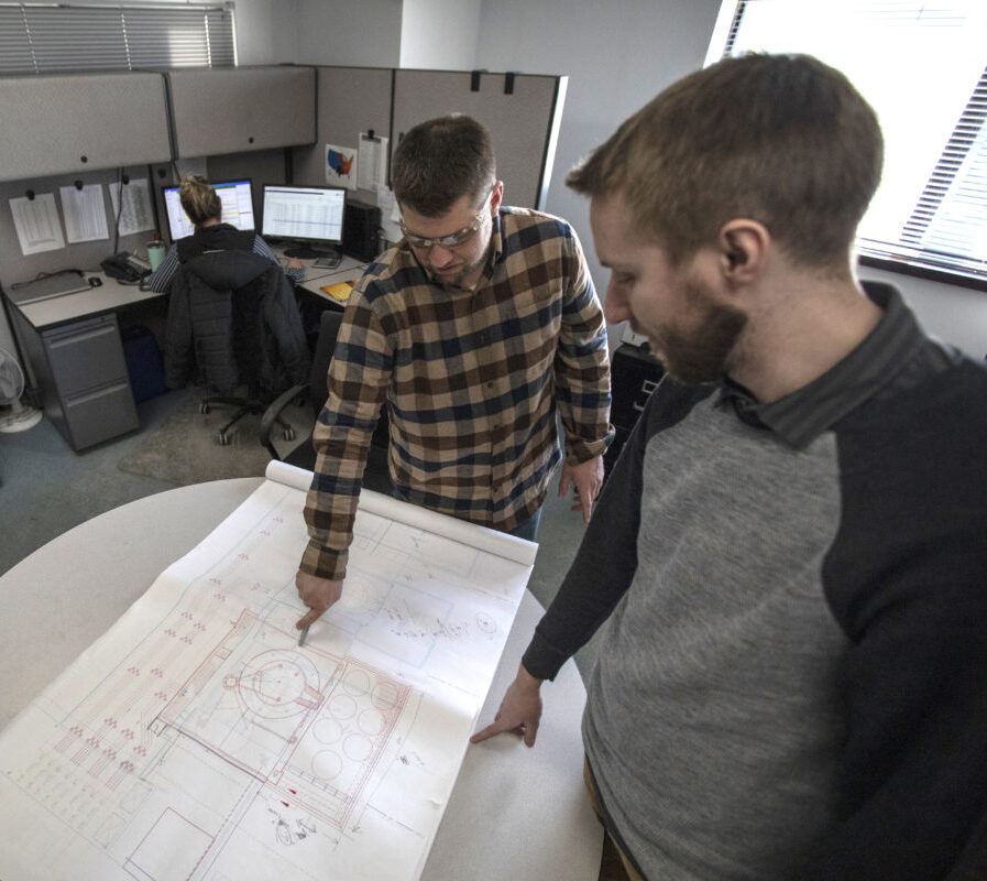 Two employees working on an engineering diagram.